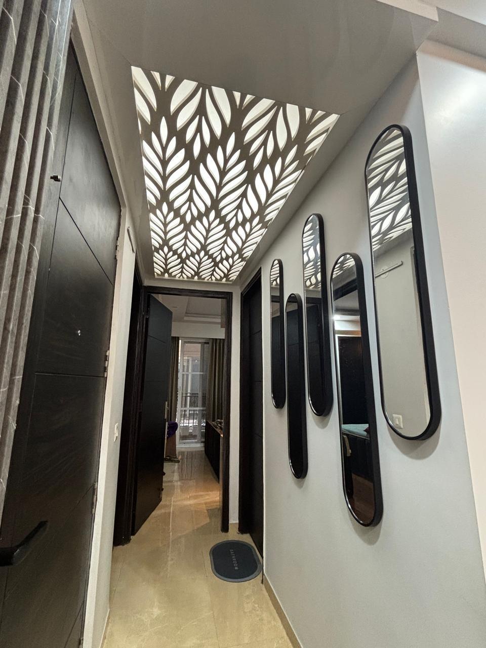 Backlit leaf-pattern false ceiling above a mirrored hallway