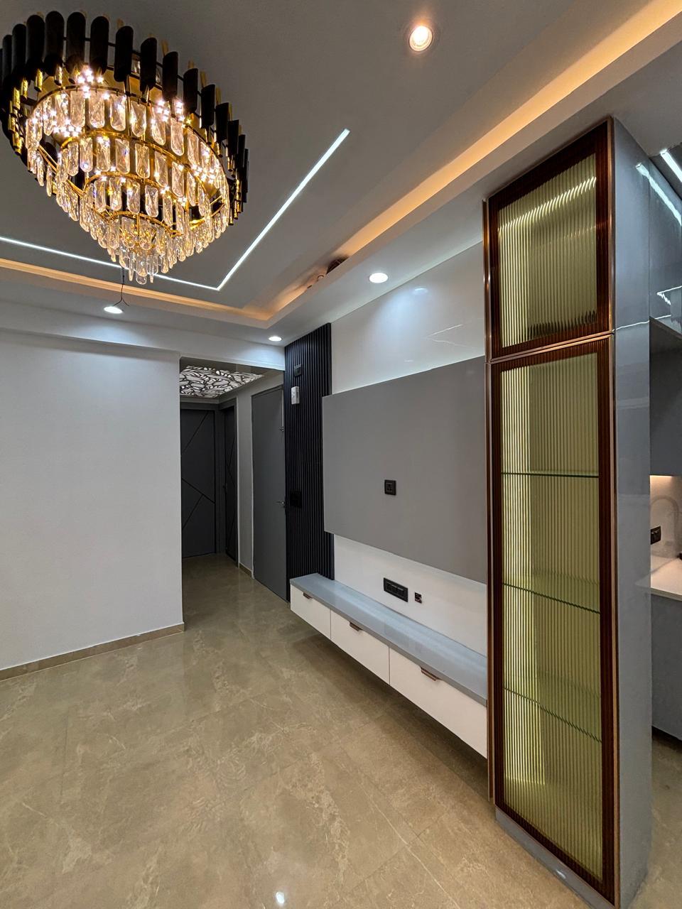 Hallway with a fluted glass display column and chandelier