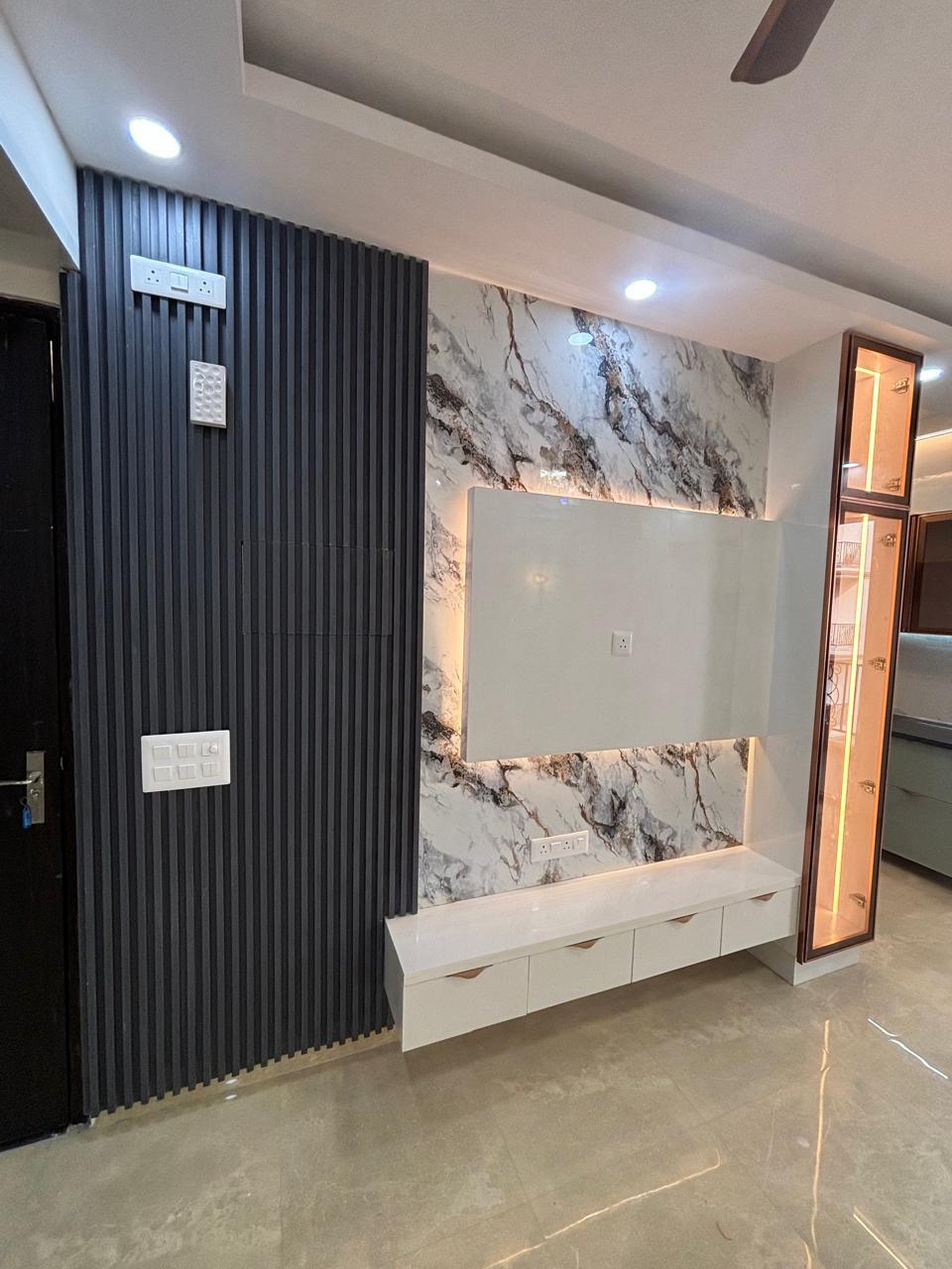 TV unit against a marble backdrop with a black slat wall