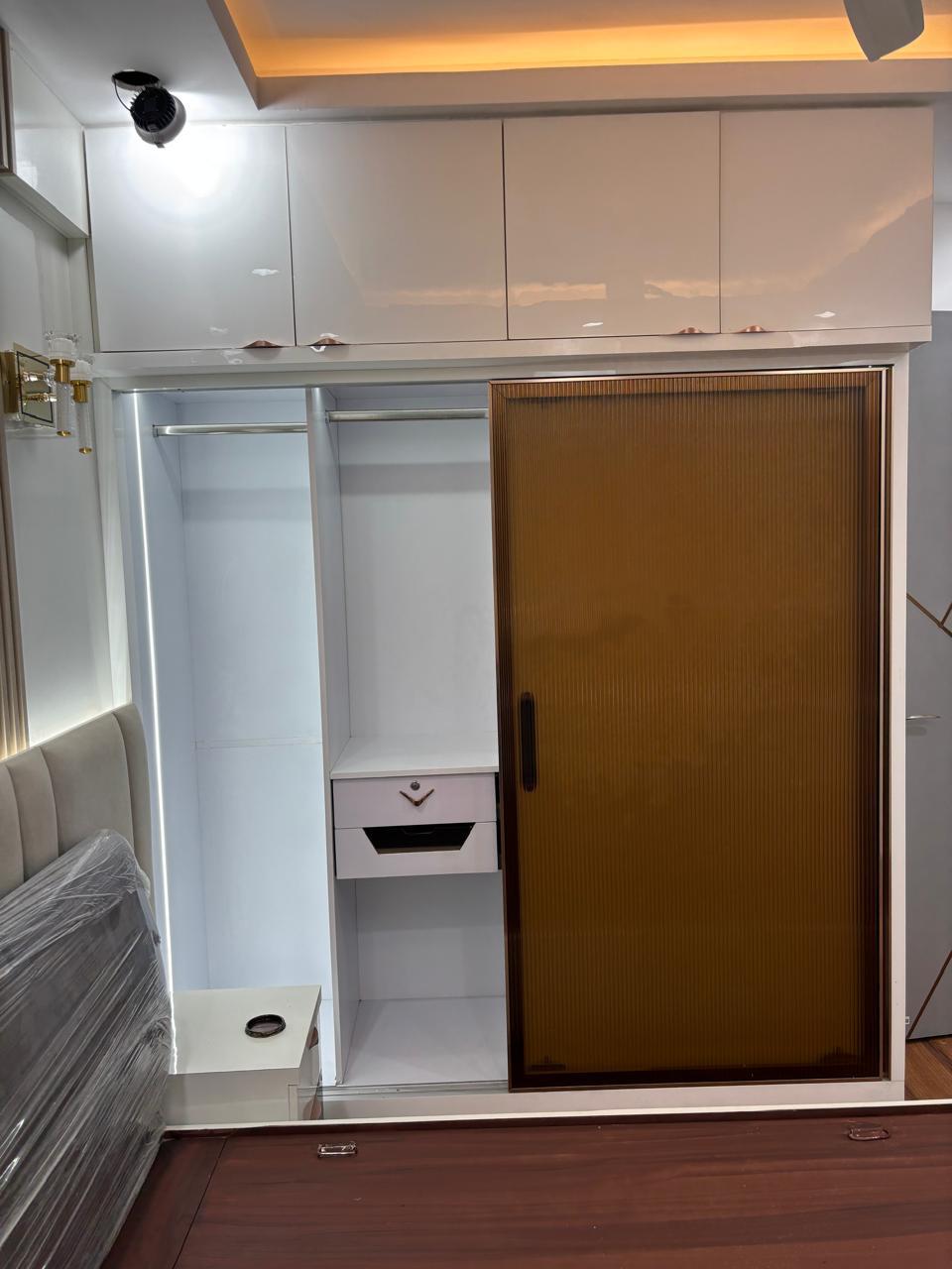 Open white wardrobe interior with hanging rail and bronze glass shutter