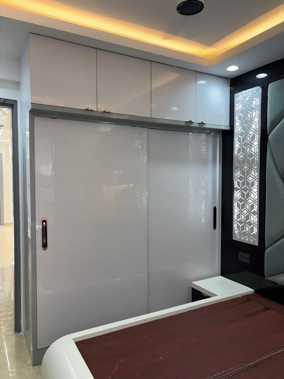 White gloss wardrobe beside a CNC jali headboard wall